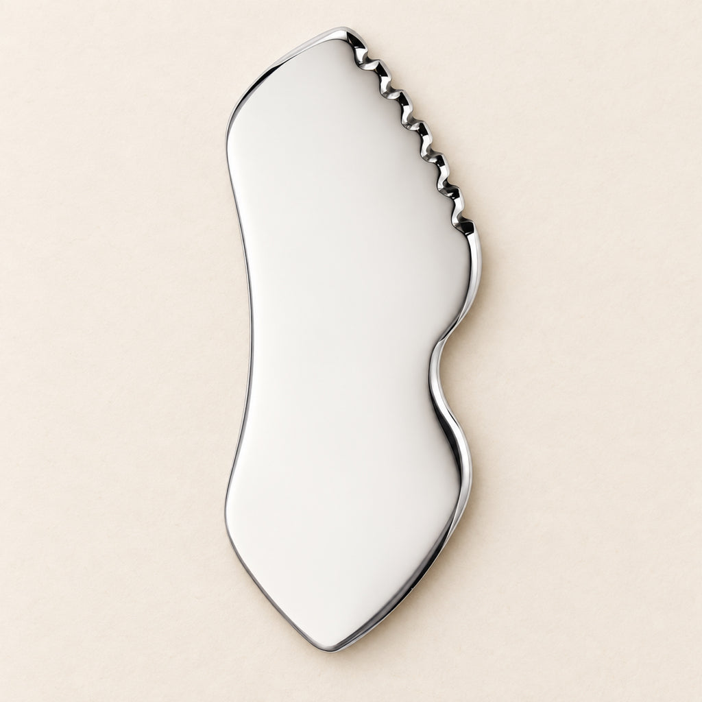 Stainless steel gua sha facial sculpting tool in a natural setting