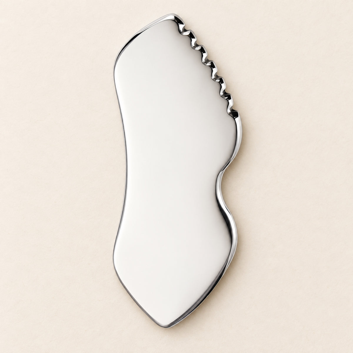 Stainless steel gua sha facial sculpting tool in a natural setting