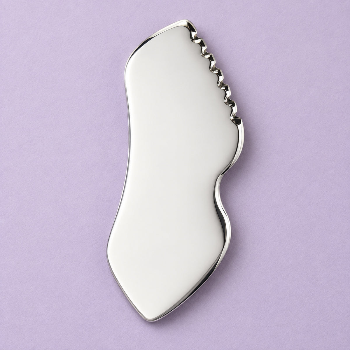 Stainless steel gua sha facial sculpting tool in a natural setting