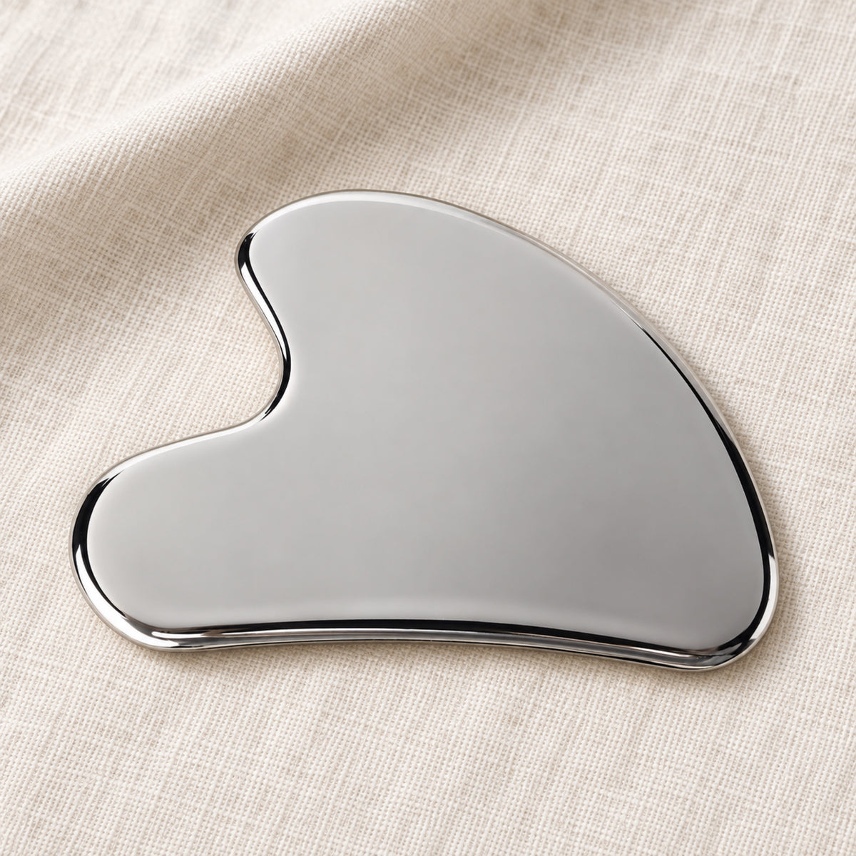 Silver wing-shaped gua sha in a natural self-care setting