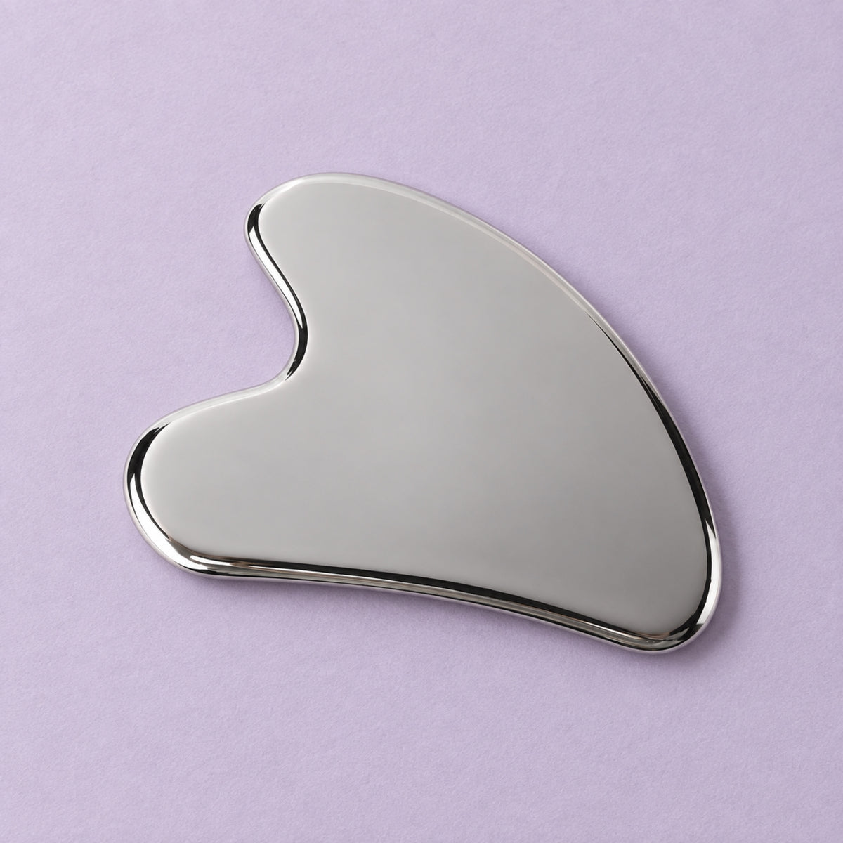 Silver wing-shaped gua sha in a natural self-care setting