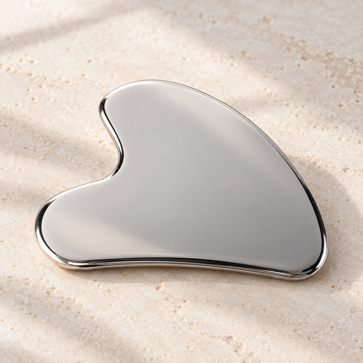 Silver wing-shaped gua sha in a natural self-care setting