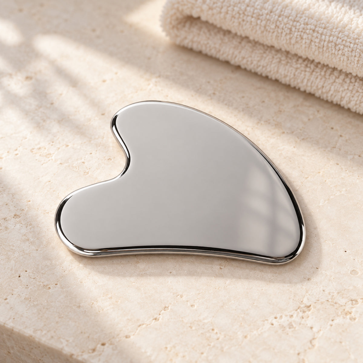 Silver wing-shaped gua sha in a natural self-care setting