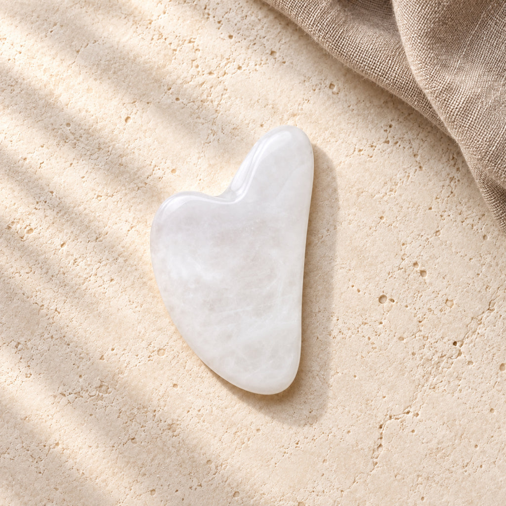 Gua Sha Facial Massage Stone - White in a wide natural setting with brown linen