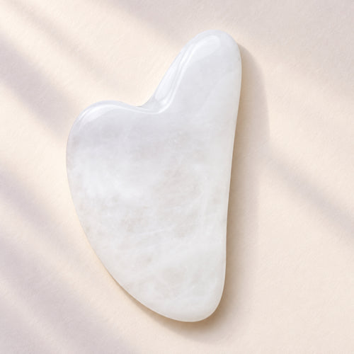 White jade gua sha facial massage tool on a soft neutral background