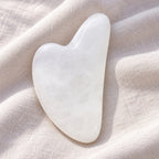 White jade gua sha facial massage tool on a soft neutral background