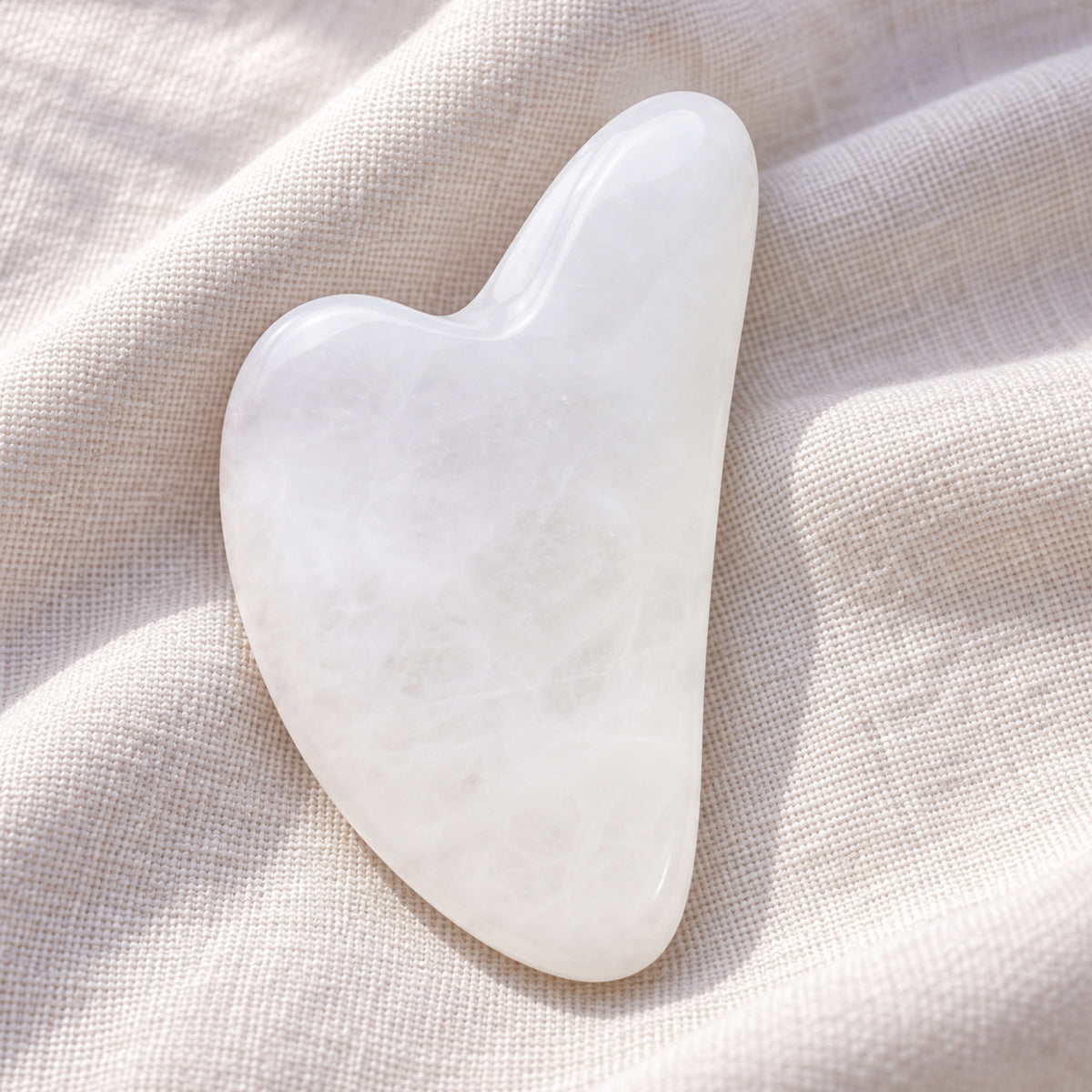 White jade gua sha facial massage tool on a soft neutral background