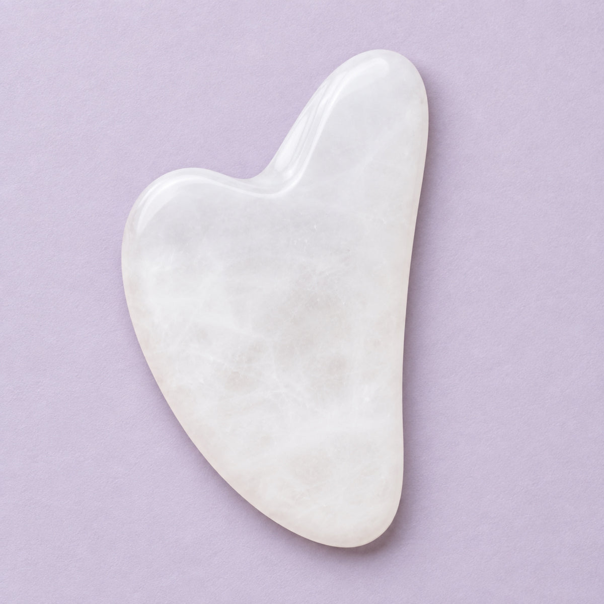 White jade gua sha facial massage tool on a soft neutral background