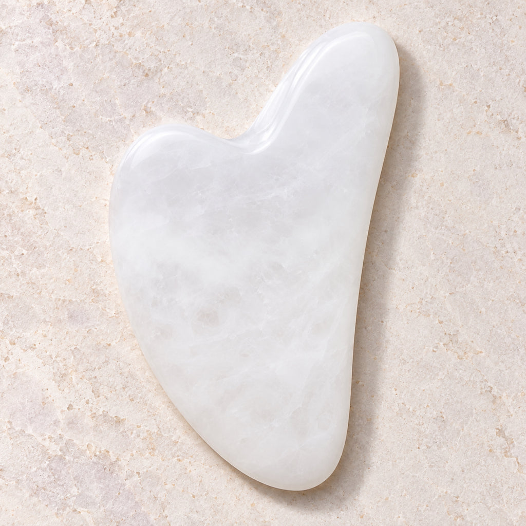 White jade gua sha facial massage tool on a soft neutral background
