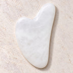 White jade gua sha facial massage tool on a soft neutral background