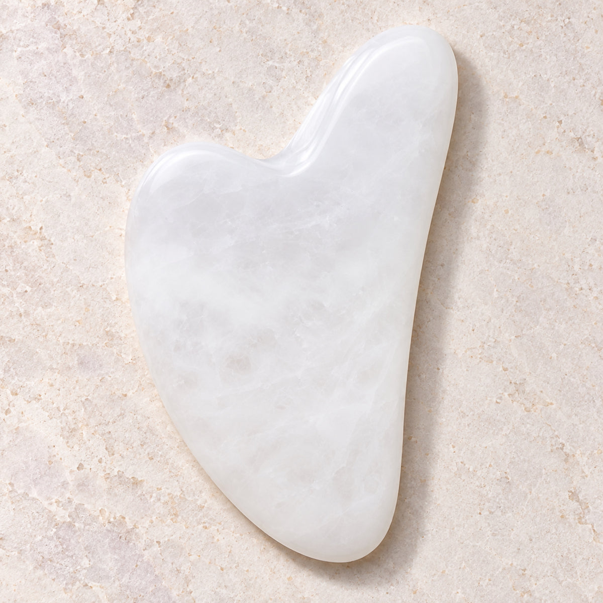 White jade gua sha facial massage tool on a soft neutral background