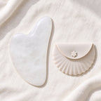 White jade gua sha facial massage tool on a soft neutral background